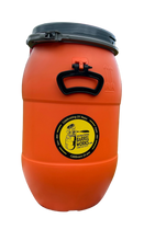 Load image into Gallery viewer, Orange barrel with a yellow label on a rock, with kayaks in the background.
