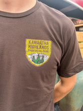Load image into Gallery viewer, Brown t-shirt with Kawartha Highlands Provincial Park logo worn by a person.
